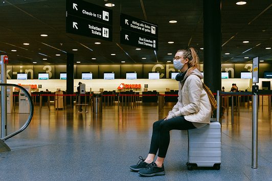 A woman sitting on top of luggage in an airport.