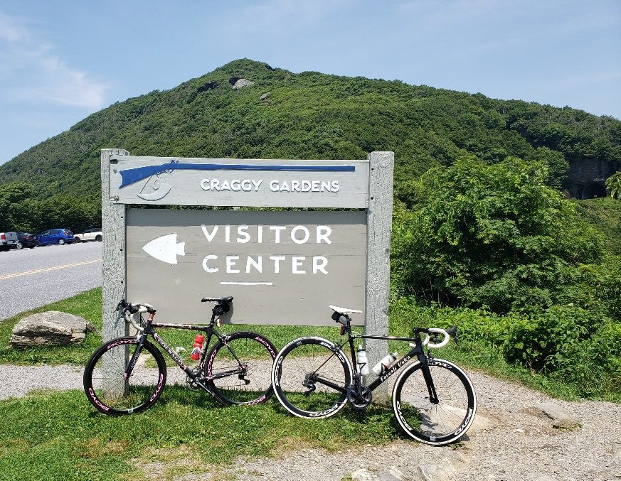 Two bicycles are parked in front of a sign.