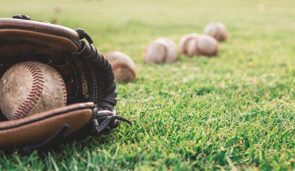 A baseball glove and some balls on the grass.