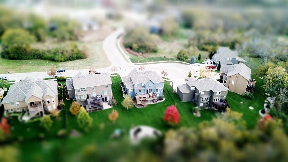 A view of houses from above with trees in the background.