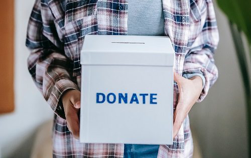 A person holding a box that says " donate ".