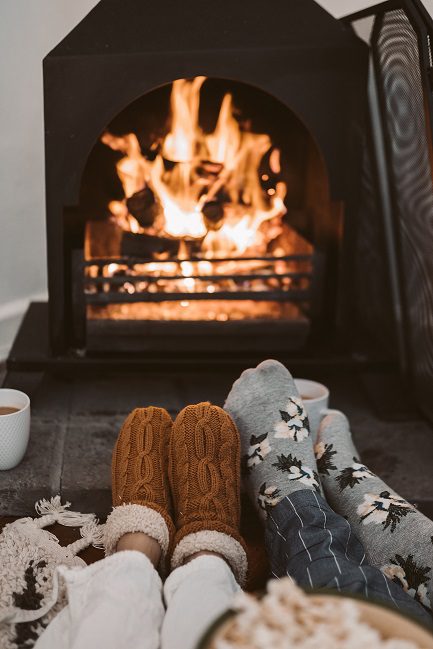 Two pairs of feet in front of a fireplace.