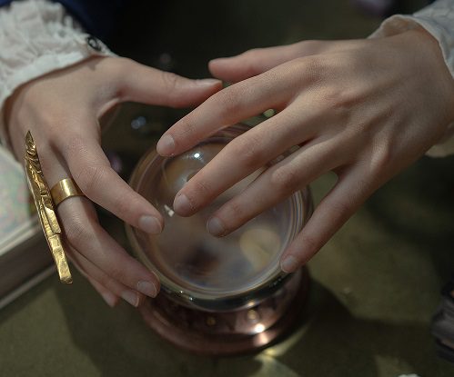 A person is holding their hands over the crystal ball.