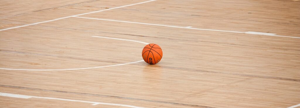 A basketball is on the court with no one around.