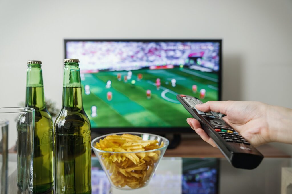 A person is holding a remote control in front of a tv.