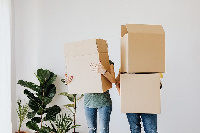 Two people holding boxes in front of their faces.