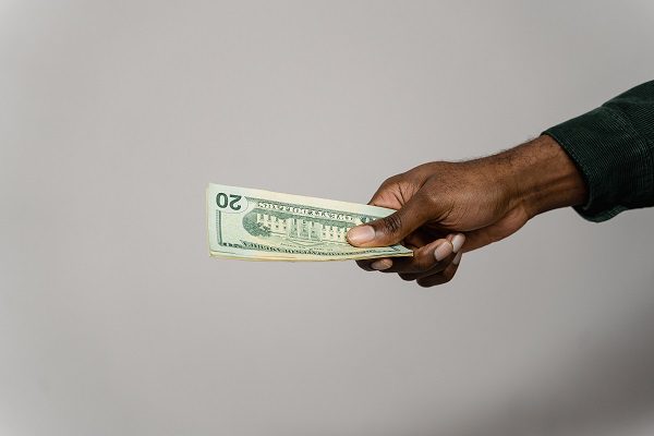 A person holding a dollar bill in their hand.