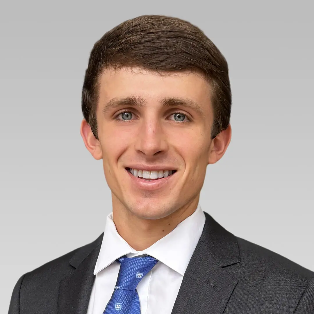 Professional young man in a suit and tie smiling at the camera.
